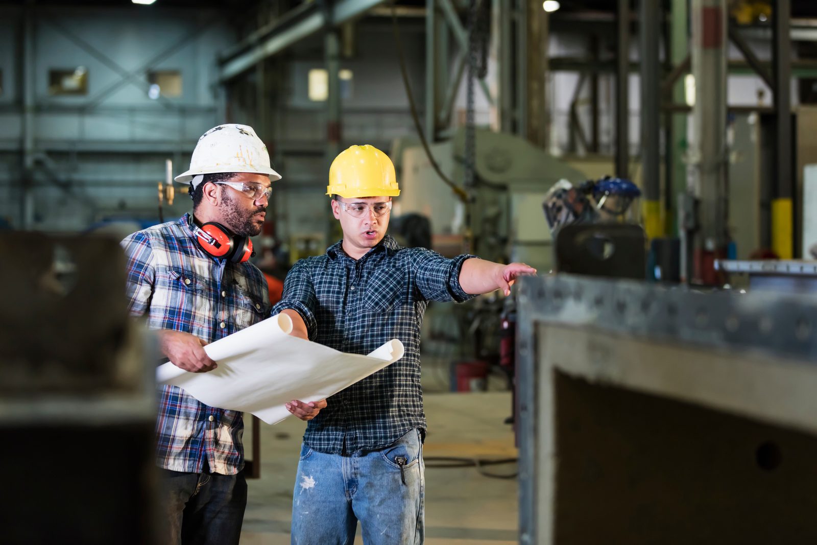 Fabrication engineers reviewing steel components on the factory floor