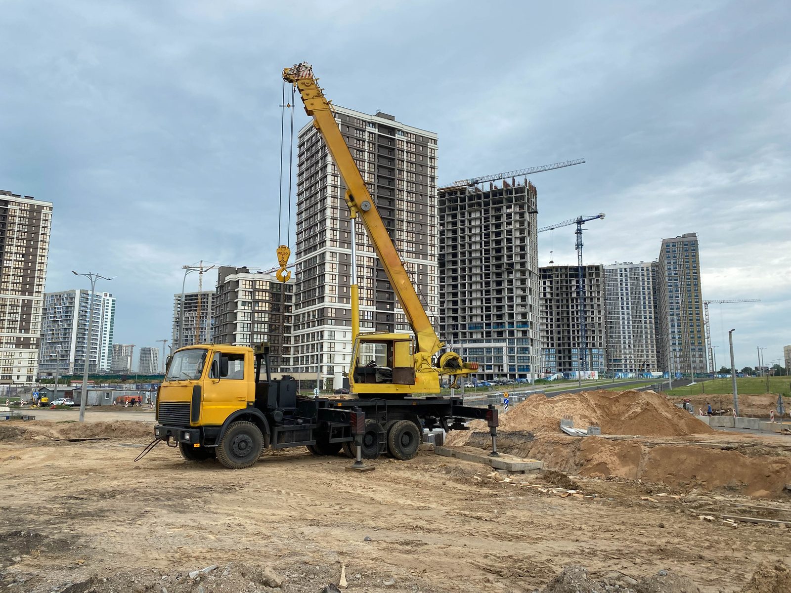 Mobile crane operating on a site with residential towers in the background